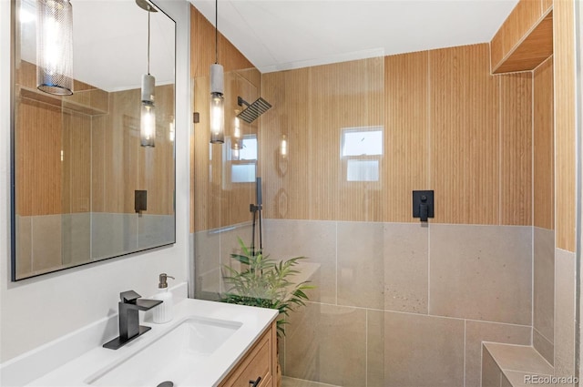 bathroom with vanity, a tile shower, and tile walls