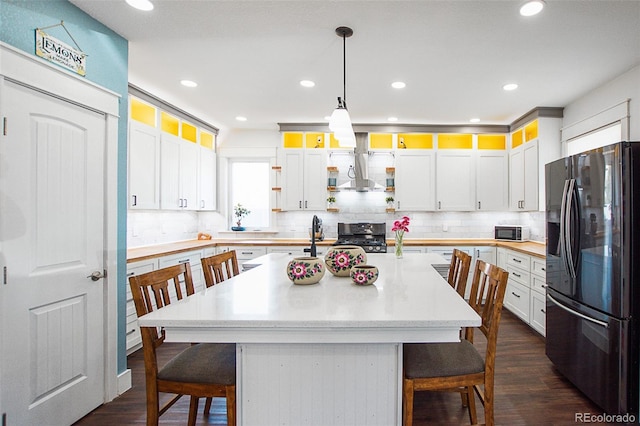 131 Faraday St, Monte Vista, CO 81144 - kitchen featuring refrigerator with ice dispenser, wall chimney range hood, range, a breakfast bar area, and decorative backsplash