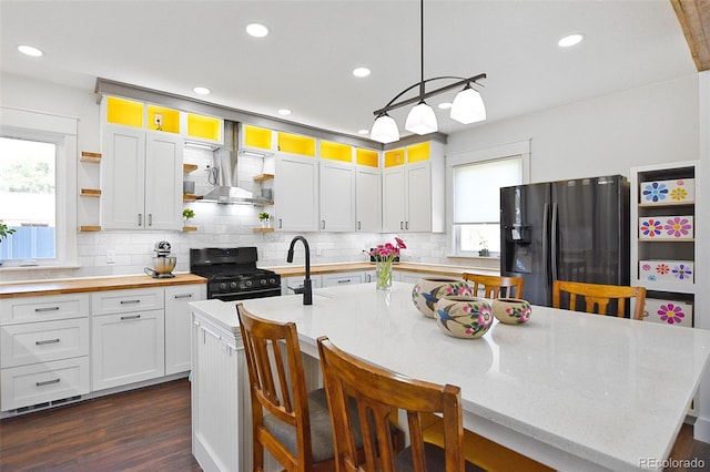 131 Faraday St, Monte Vista, CO 81144 - kitchen featuring black refrigerator with ice dispenser, open shelves, wall chimney exhaust hood, gas range, and dark wood-style flooring
