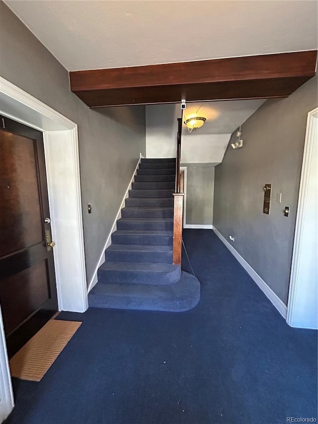 staircase with beamed ceiling and concrete flooring