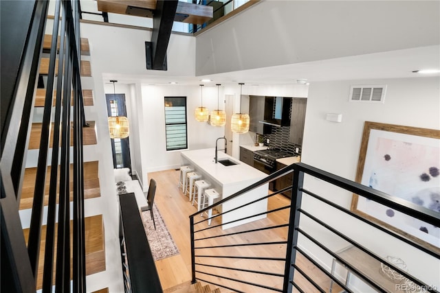 staircase featuring sink, hardwood / wood-style floors, and a high ceiling