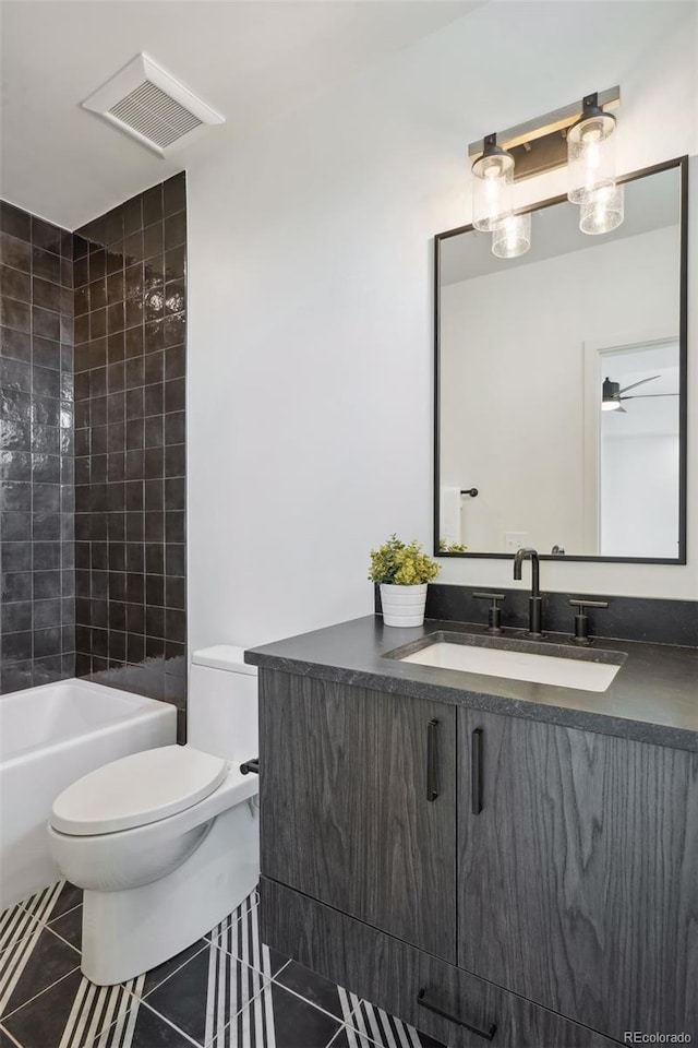 full bathroom with tile patterned floors, toilet, tiled shower / bath combo, and vanity