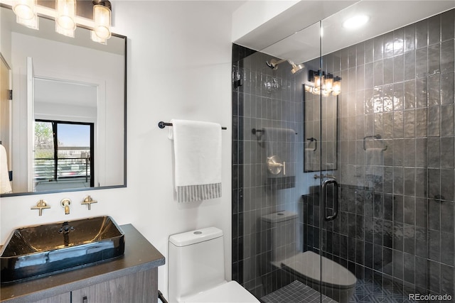 bathroom with vanity, a shower with shower door, and toilet