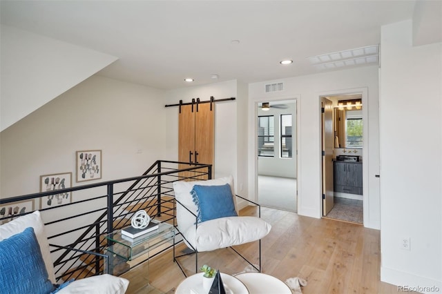 living area featuring a barn door and light hardwood / wood-style floors