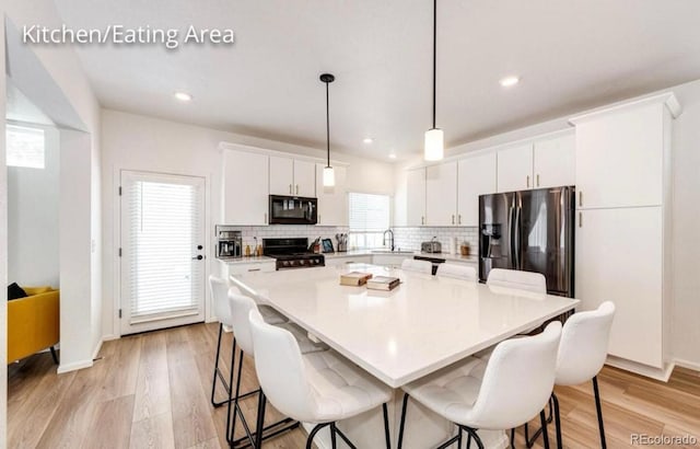 4443 N Quatar Ct, Aurora, CO 80019 - kitchen with black microwave, stainless steel fridge with ice dispenser, range, tasteful backsplash, and a kitchen bar