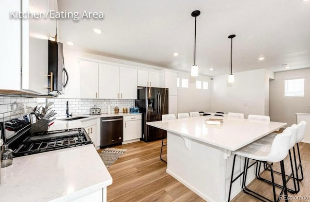 4443 N Quatar Ct, Aurora, CO 80019 - kitchen featuring appliances with stainless steel finishes, a kitchen bar, decorative backsplash, white cabinetry, and light countertops