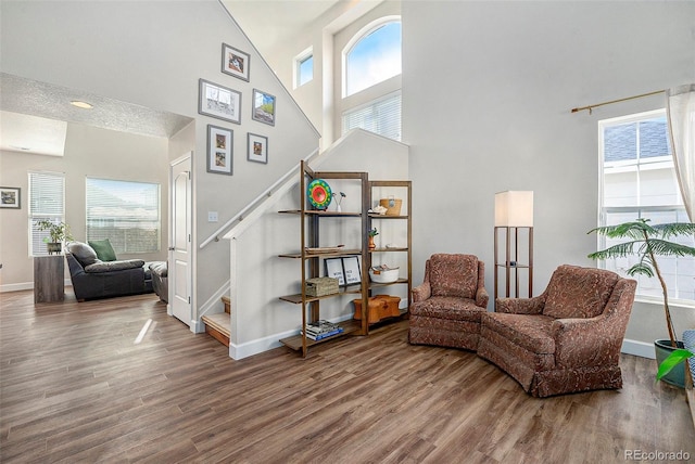 living area featuring baseboards, a high ceiling, stairway, and wood finished floors