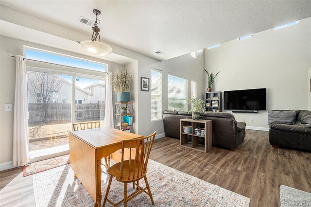 dining space with a textured ceiling, visible vents, and wood finished floors