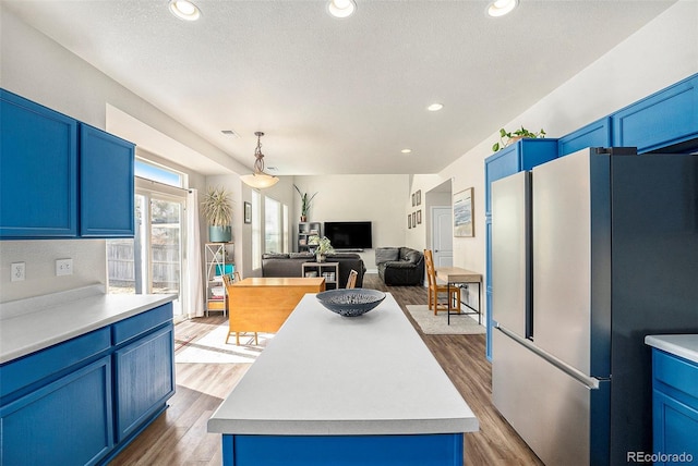 kitchen featuring wood finished floors, freestanding refrigerator, and blue cabinets