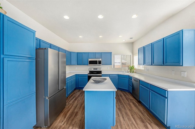 kitchen featuring dark wood-style flooring, blue cabinetry, light countertops, appliances with stainless steel finishes, and a kitchen island