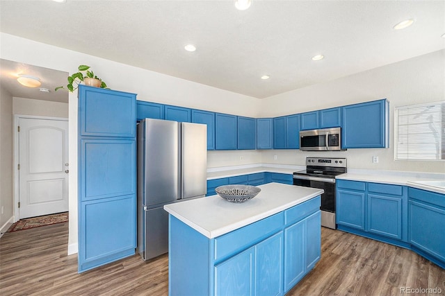 kitchen featuring a center island, blue cabinetry, stainless steel appliances, light countertops, and wood finished floors