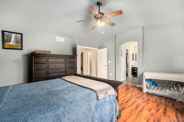 bedroom with arched walkways, visible vents, a ceiling fan, vaulted ceiling, and wood finished floors