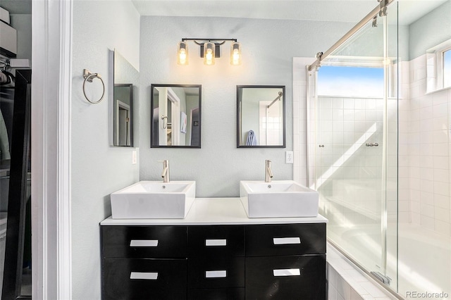 bathroom featuring tiled shower / bath, double vanity, and a sink