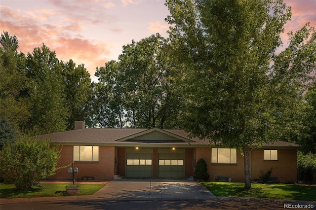 single story home with concrete driveway, a lawn, an attached garage, crawl space, and brick siding