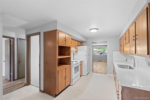 kitchen with white appliances, light floors, light countertops, under cabinet range hood, and a sink