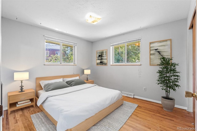 bedroom with light wood-style flooring, multiple windows, visible vents, and baseboards