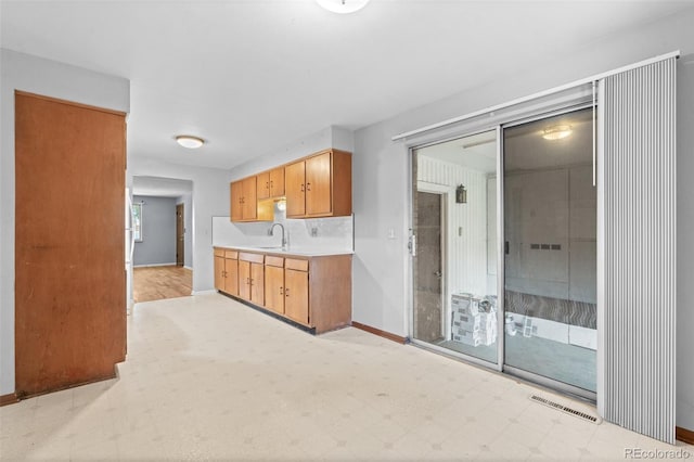 kitchen featuring baseboards, visible vents, light countertops, light floors, and a sink