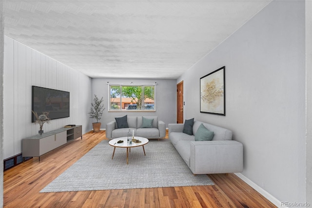 living area with baseboards and wood finished floors