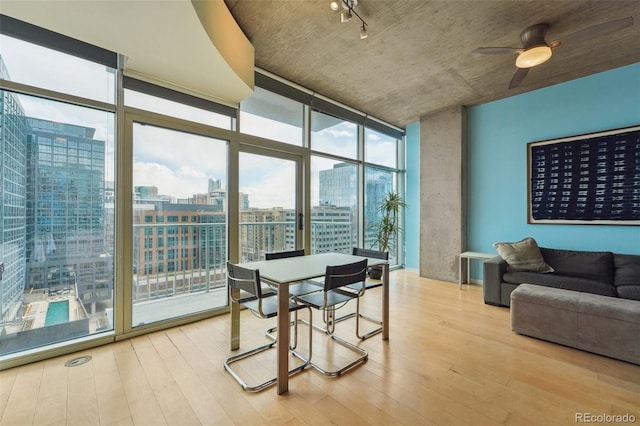 dining space featuring light hardwood / wood-style floors, a wall of windows, and ceiling fan