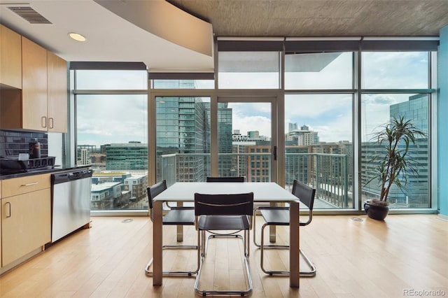 dining room with a wealth of natural light, light wood-type flooring, and a wall of windows