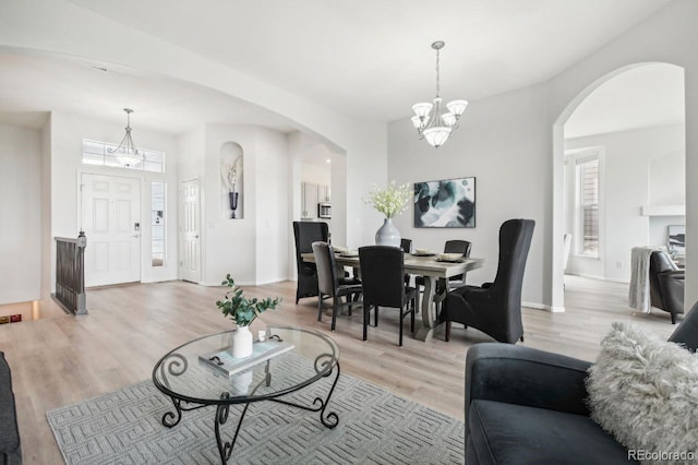 living room with a chandelier, light hardwood / wood-style floors, and a healthy amount of sunlight