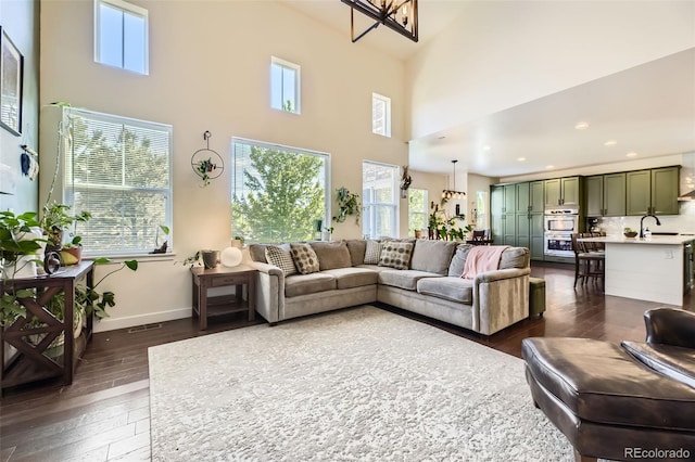 26591 E Calhoun Pl, Aurora, CO 80016 - living room with healthy amount of natural light, dark wood-type flooring, a high ceiling, recessed lighting, and a chandelier
