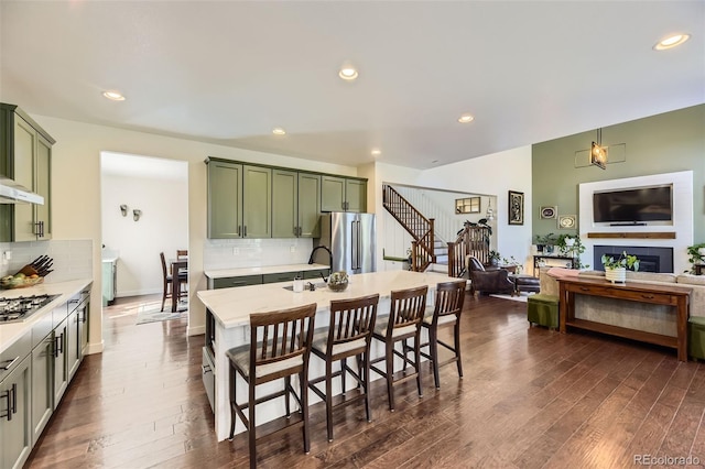 26591 E Calhoun Pl, Aurora, CO 80016 - kitchen featuring green cabinets, appliances with stainless steel finishes, dark wood finished floors, open floor plan, and recessed lighting