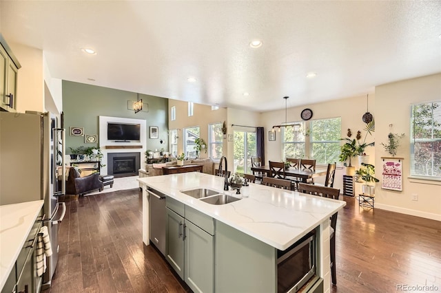 26591 E Calhoun Pl, Aurora, CO 80016 - kitchen with appliances with stainless steel finishes, open floor plan, dark wood finished floors, a kitchen island with sink, and recessed lighting