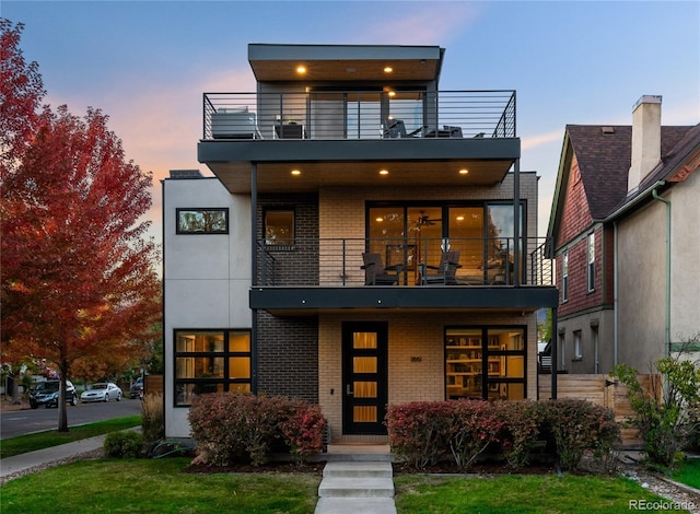 contemporary house featuring a balcony and a lawn