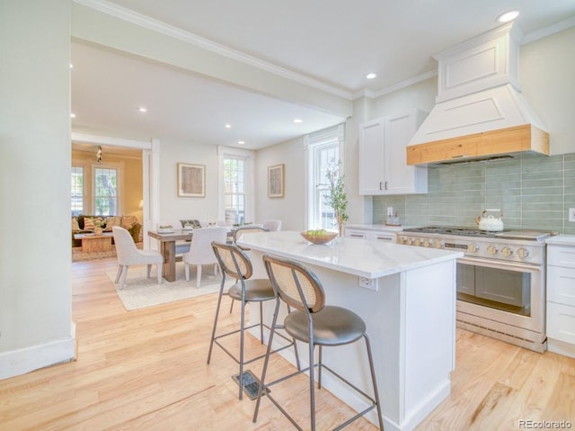 541 Fox St, Denver, CO 80204 - kitchen with high end stainless steel range, light wood-style flooring, a kitchen bar, white cabinets, and recessed lighting