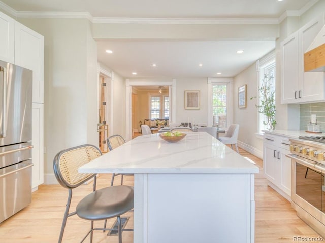 541 Fox St, Denver, CO 80204 - kitchen with appliances with stainless steel finishes, light wood finished floors, a kitchen breakfast bar, a kitchen island, and recessed lighting