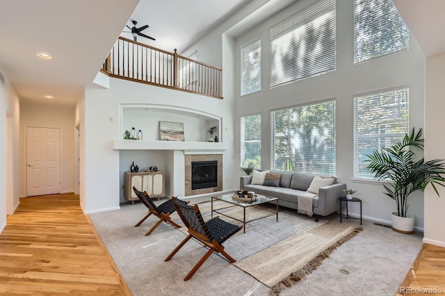 11729 Elmer Linn Dr, Longmont, CO 80504 - living room featuring healthy amount of natural light, ceiling fan, light wood finished floors, a tiled fireplace, and a high ceiling