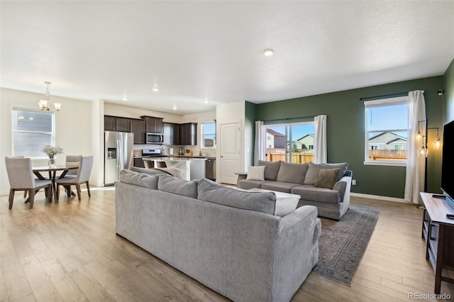 living room with recessed lighting, light wood-style flooring, baseboards, and an inviting chandelier