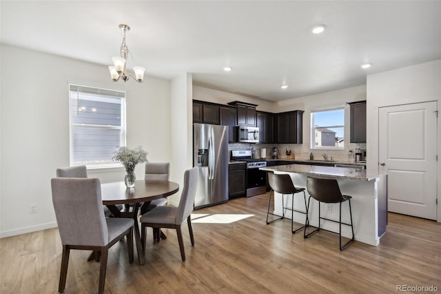 dining space with a chandelier, recessed lighting, light wood-style flooring, and baseboards