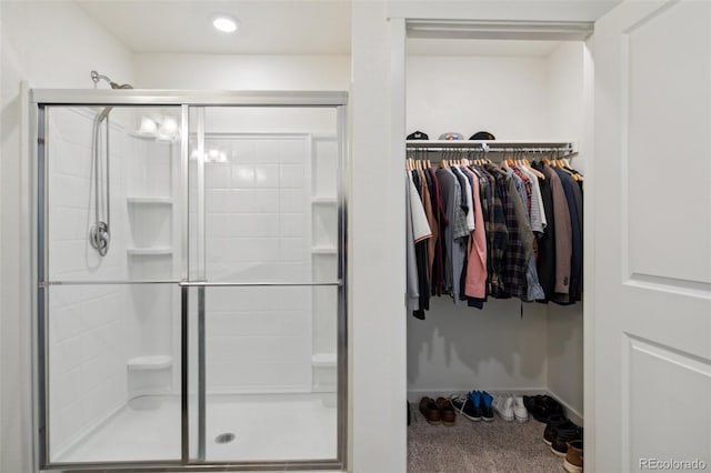 bathroom featuring a spacious closet, a shower stall, and baseboards