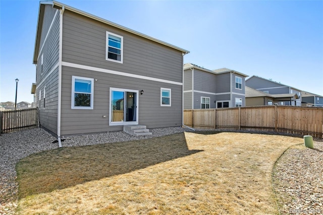 rear view of house featuring entry steps and a fenced backyard