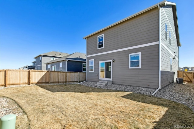 rear view of house featuring entry steps, a fenced backyard, and central air condition unit