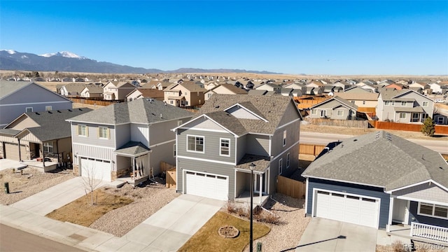 view of front of home with a mountain view, concrete driveway, fence, and a residential view