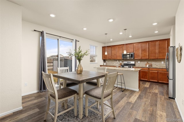 kitchen with a kitchen breakfast bar, backsplash, stainless steel appliances, a center island, and hanging light fixtures