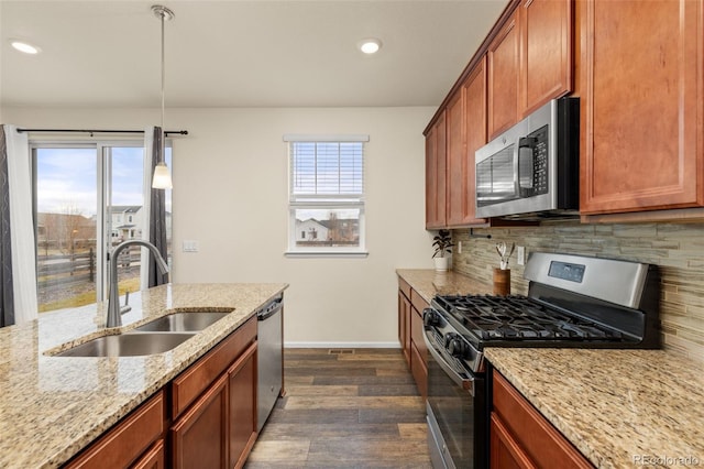 kitchen featuring light stone countertops, sink, stainless steel appliances, decorative light fixtures, and decorative backsplash