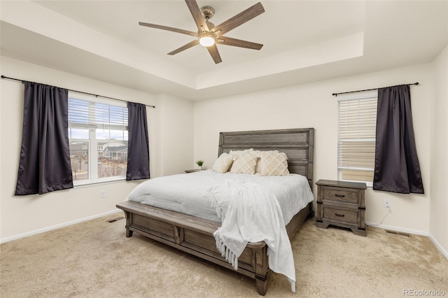 carpeted bedroom featuring a tray ceiling and ceiling fan