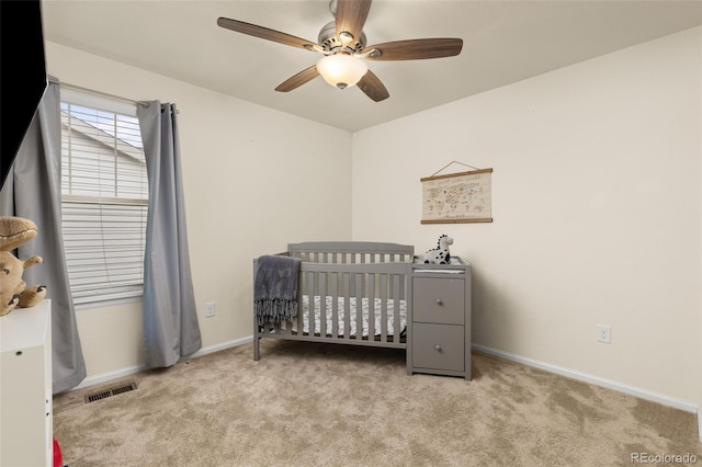 bedroom with light carpet, a nursery area, and ceiling fan