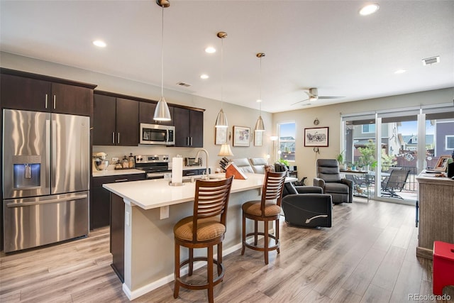 3022 Merlin Dr, Brighton, CO 80601 - kitchen with stainless steel appliances, open floor plan, light countertops, a kitchen breakfast bar, and light wood finished floors