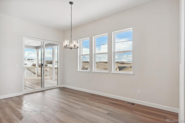 unfurnished dining area featuring wood-type flooring and an inviting chandelier