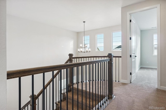 hall featuring carpet flooring and an inviting chandelier