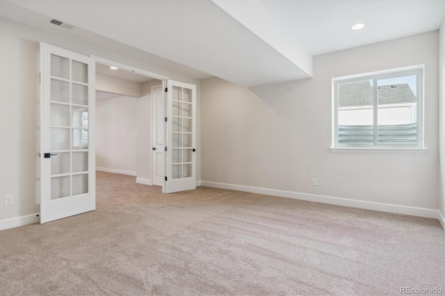 spare room featuring french doors and light colored carpet