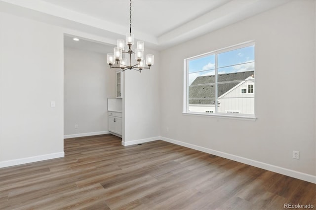 unfurnished dining area featuring a chandelier and hardwood / wood-style floors