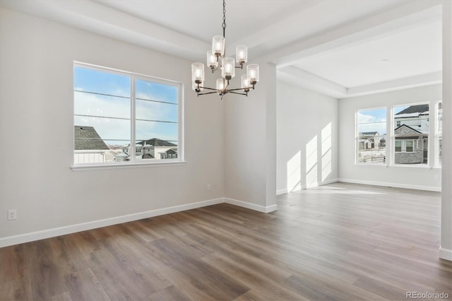 spare room with a raised ceiling, a chandelier, and wood-type flooring