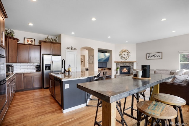 15502 E Flower Mound Pl, Parker, CO 80134 - kitchen featuring stainless steel appliances, open floor plan, a kitchen island with sink, light wood finished floors, and recessed lighting