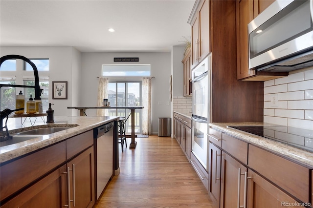 15502 E Flower Mound Pl, Parker, CO 80134 - kitchen featuring stainless steel appliances, light wood-type flooring, decorative backsplash, light stone counters, and recessed lighting